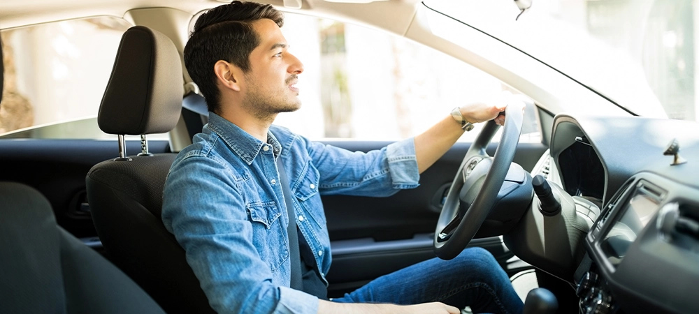 handsome young man driving his car on city street
