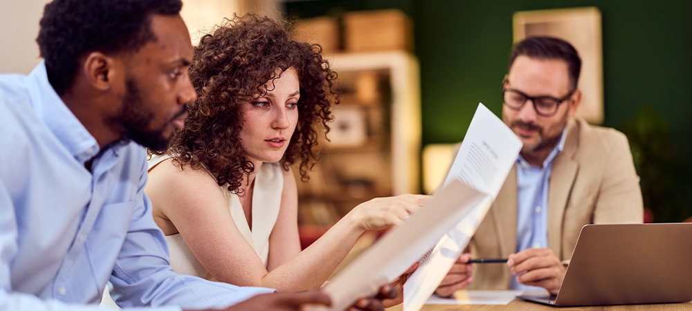 Professional discussion between an insurance agent and clients in a friendly office setting.