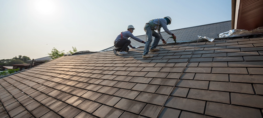 Roofer worker in special protective work wear and gloves, Using pneumatic gun and repair and replace roof tile on top of the new roof.