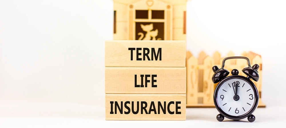 Term life insurance symbol. Concept words Term life insurance on beautiful wooden blocks. Beautiful white table white background. Black alarm clock. Medical term life insurance concept. Copy space.